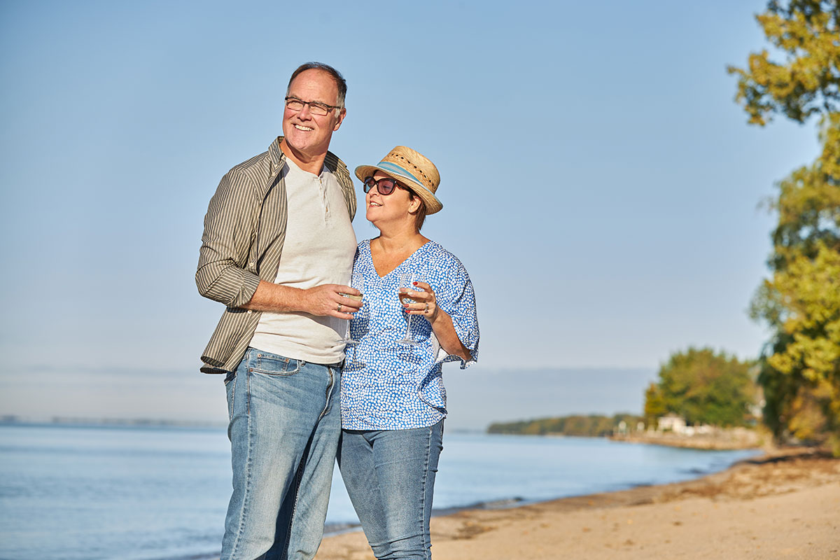 Couple looking at water on beach with wine glass