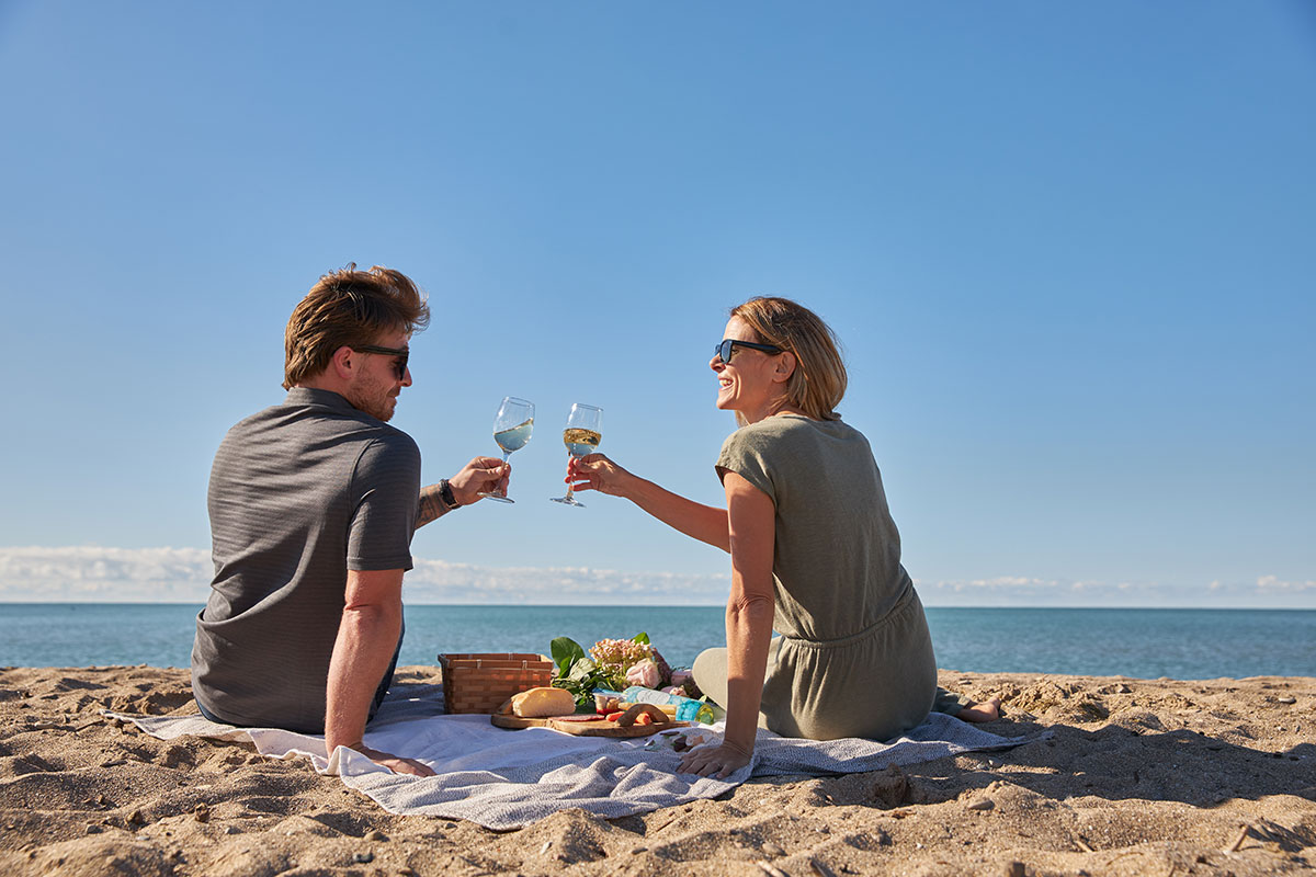 Couple celebrating on beach with glasses of wine